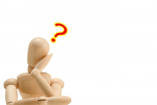 頬杖をついて疑問符を浮かべる木の人形